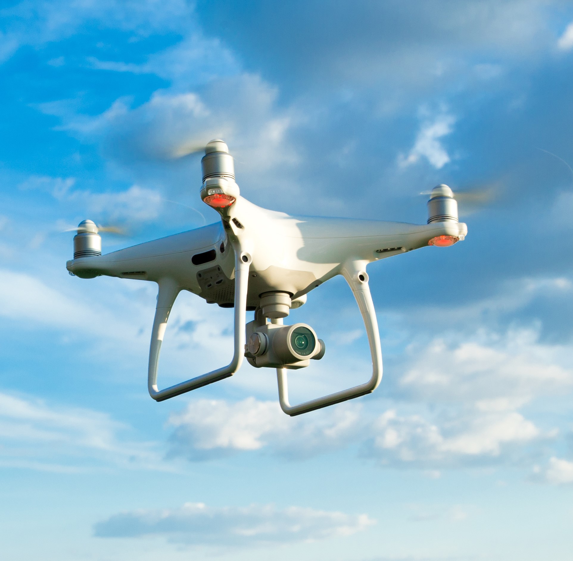 Drone flying overhead in cloudy blue sky