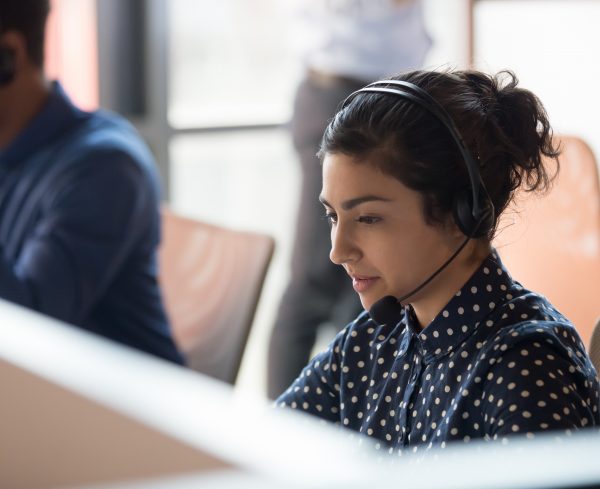 Focused indian female professional helpline call center agent operator telemarketer wear wireless headset work in customer care support service team office talking consulting client at workplace