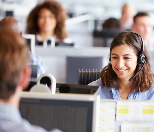 Young woman working in call centre, surrounded by colleagues
