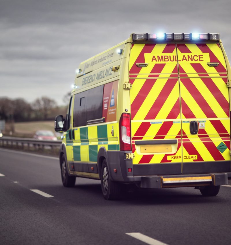 British ambulance responding to an emergency in hazardous bad weather driving conditions on a UK motorway