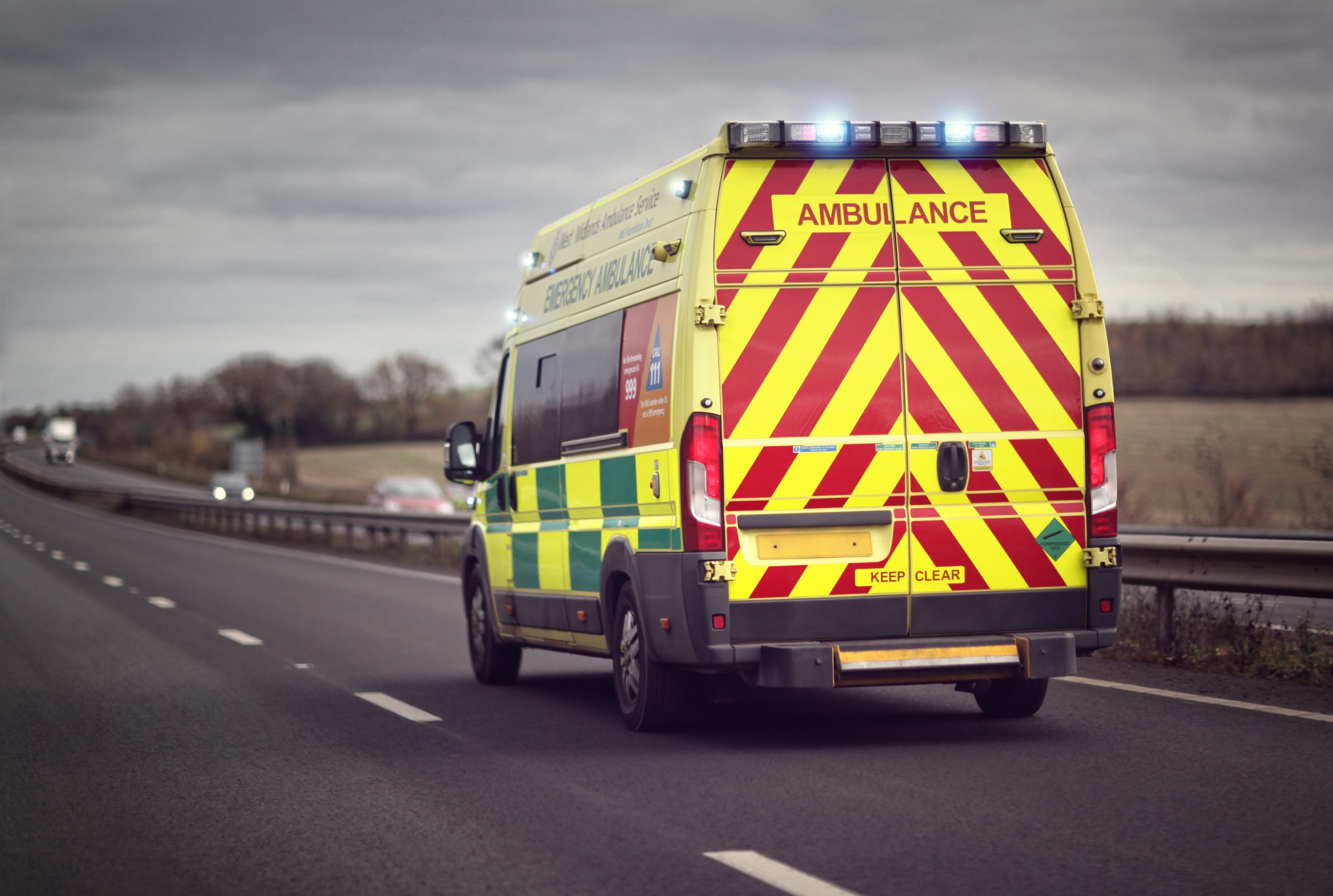 British ambulance responding to an emergency in hazardous bad weather driving conditions on a UK motorway